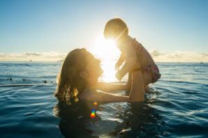 Woman playing with her little baby in a swimming pool at sunset, Papeete, Tahiti, French Polynesia Woman playing with her little baby in a swimming pool at sunset, Papeete, Tahiti, French Polynesia